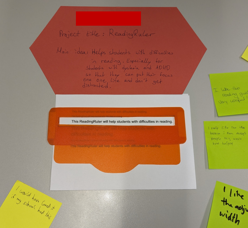 A reading ruler (A ruler like object with a window in it) from red transparent plastic, overlaid over a same text. Card with project info and post-its with feedback